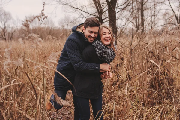 Liebendes junges Paar glücklich zusammen draußen auf gemütlich warmem Spaziergang im herbstlichen Wald — Stockfoto