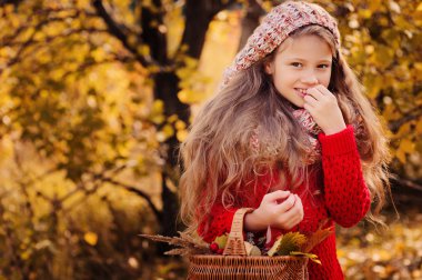 mutlu çocuk kız örgü atkı ve kazak sepeti sonbahar yürüyüş orman yeme elma ile. Sonbaharda hasat, rahat ruh hali.