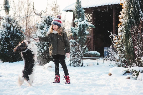 Enfant fille s'amuser et jouer avec son chien dans le jardin enneigé — Photo