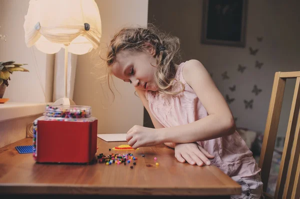 Niña feliz jugando con mosaico en casa en su habitación — Foto de Stock