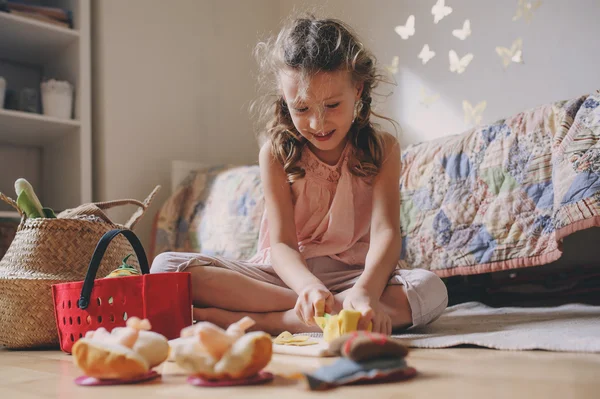 Yemek ve having fun evde oyuncak yiyeceklerle odasında oynarken küçük kız çocuk — Stok fotoğraf