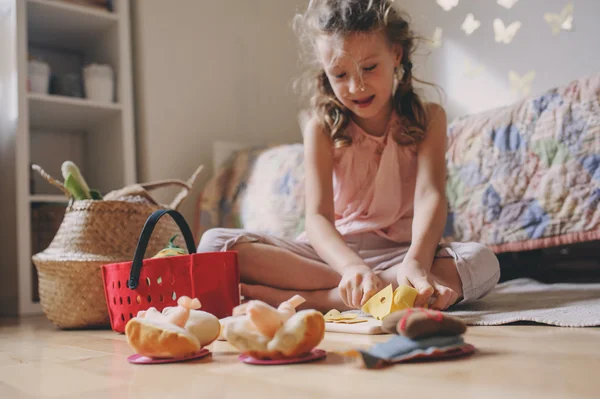 Yemek ve having fun evde oyuncak yiyeceklerle odasında oynarken küçük kız çocuk — Stok fotoğraf