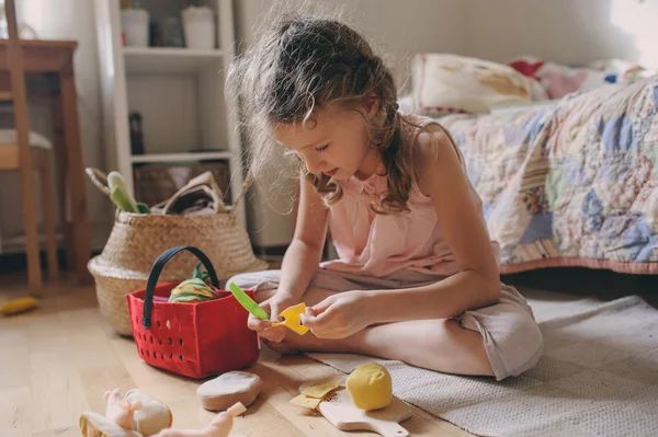 Little child girl playing in her room with toy food, cooking and having fun at home — Stock Photo, Image