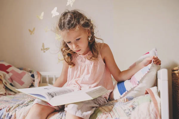 孩子坐在床上和她的房间里读书的女孩。舒适周末在家，生活方式捕获 — 图库照片