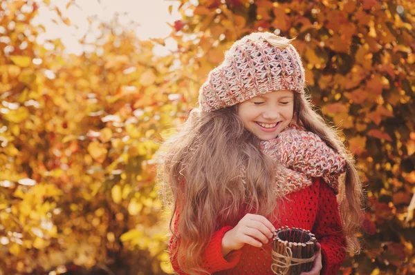 Fröhliches Kindermädchen in Strickschal und Pullover mit Korb beim Herbstspaziergang im Wald — Stockfoto