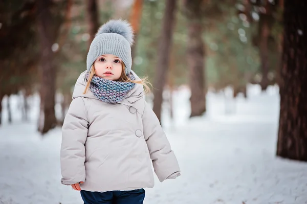 Winter portrait of cute baby girl walking outdoor in snowy forest in warm outfit — Stock Photo, Image