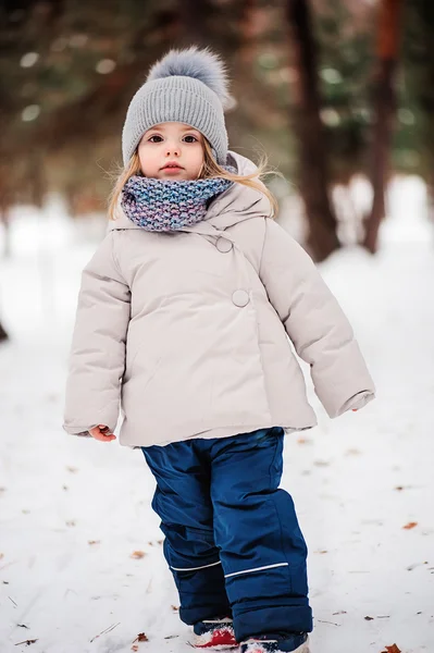 Vinter porträtt av söt baby flicka promenader utomhus i snöiga skogen i varma outfit — Stockfoto