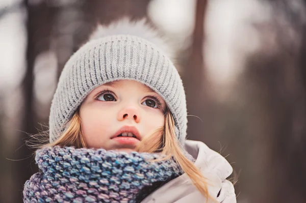 Winter portret van schattige babymeisje buiten wandelen in besneeuwde woud in warme outfit — Stockfoto