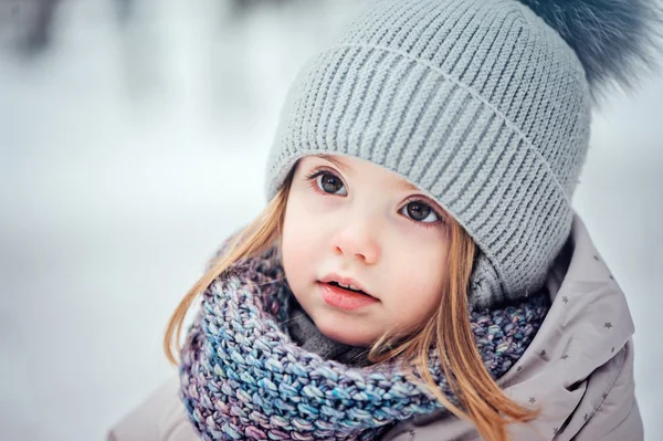 Vinter porträtt av söt baby flicka promenader utomhus i snöiga skogen i varma outfit — Stockfoto