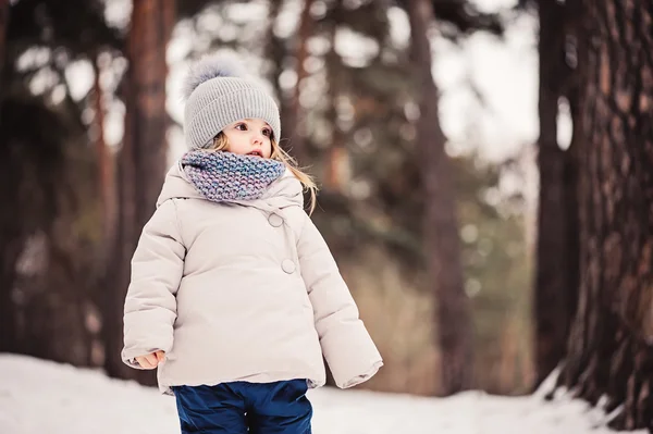 Vinter porträtt av söt baby flicka promenader utomhus i snöiga skogen i varma outfit — Stockfoto