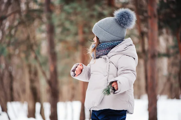 Милая счастливая девочка, гуляющая в зимнем лесу — стоковое фото