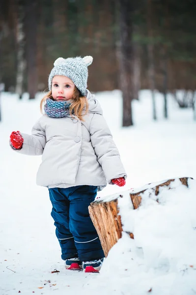 Winter portrait of beautiful baby girl in warm oversize knitted scarf and hat on the walk in snowy winter forest — Stock Photo, Image