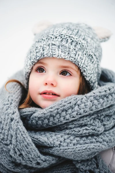 Winter-Porträt der schönen Baby-Mädchen in warmen übergroßen gestrickten Schal und Mütze auf dem Spaziergang im verschneiten Winterwald — Stockfoto