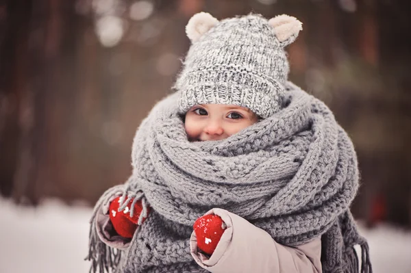 Winter portret van mooie babymeisje in warme oversize gebreide sjaal en muts op de wandeling in de winter van de besneeuwde forest — Stockfoto