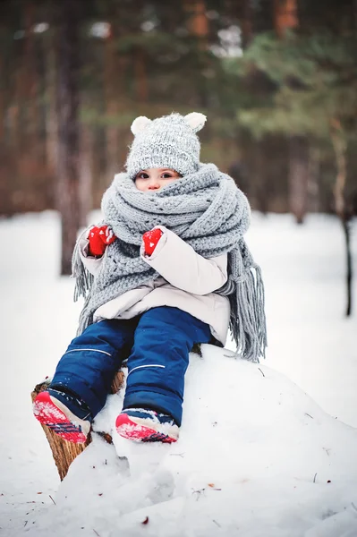 Winter portrait of beautiful baby girl in warm oversize knitted scarf and hat on the walk in snowy winter forest — Stock Photo, Image