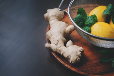 zencefil ve limon sıcak çay veya limonata karanlık rustik iç ahşap plaka üzerinde yemek pişirmek için malzemeler. 