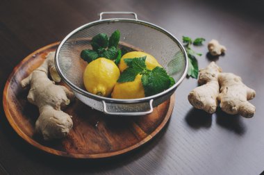 zencefil ve limon sıcak çay veya limonata karanlık rustik iç ahşap plaka üzerinde yemek pişirmek için malzemeler. 