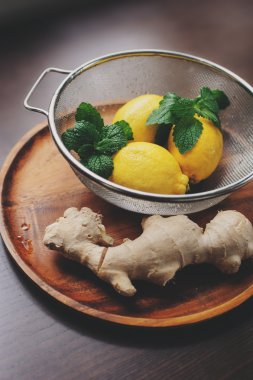 zencefil ve limon sıcak çay veya limonata karanlık rustik iç ahşap plaka üzerinde yemek pişirmek için malzemeler. 