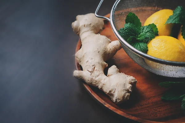 zencefil ve limon sıcak çay veya limonata karanlık rustik iç ahşap plaka üzerinde yemek pişirmek için malzemeler. 