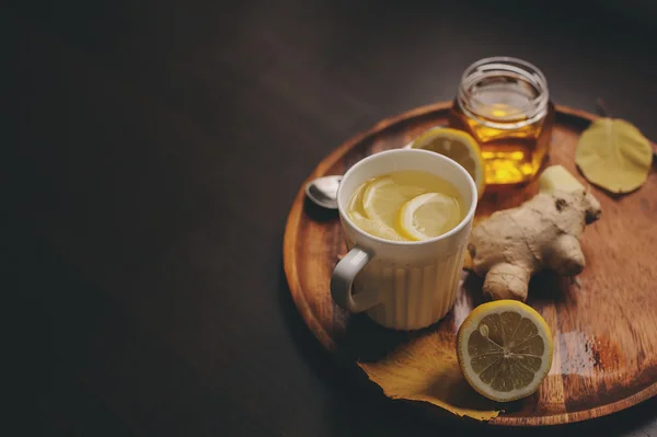 stock image cooking ginger, lemon and honey hot tea in dark rustic interior. Ingredients and cup on wooden background