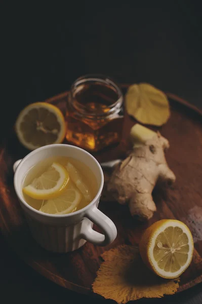Koken hete thee van gember, citroen en honing in donkere rustieke interieur. Ingrediënten en cup op houten achtergrond — Stockfoto