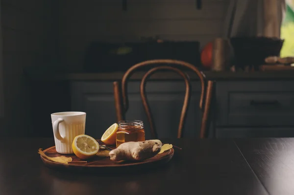 Cocina de jengibre, limón y té caliente de miel en el interior rústico oscuro. Ingredientes y taza sobre fondo de madera —  Fotos de Stock