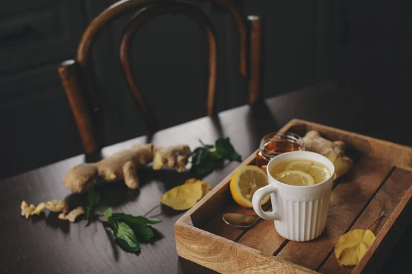Memasak jahe, lemon dan teh madu panas di pedesaan gelap interior. Bahan-bahan dan cangkir pada latar belakang kayu — Stok Foto
