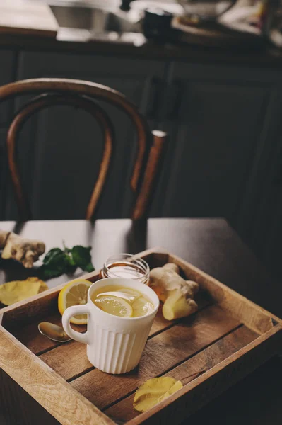 Cottura di zenzero, limone e miele tè caldo in interni rustici scuri. Ingredienti e coppa su fondo di legno — Foto Stock