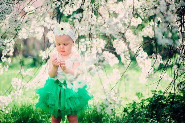 Frühling Porträt von niedlichen Baby-Mädchen in grünem Rock genießen Spaziergang im Freien in blühenden Garten — Stockfoto