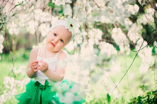 Retrato de primavera de linda niña en falda verde disfrutando de paseo al aire libre en el jardín floreciente — Foto de Stock