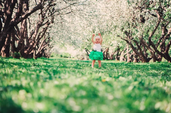 Άνοιξη πορτρέτο του χαριτωμένο κοριτσάκι σε πράσινη φούστα απόλαυση υπαίθρια βόλτα στον ολάνθιστο κήπο — Φωτογραφία Αρχείου