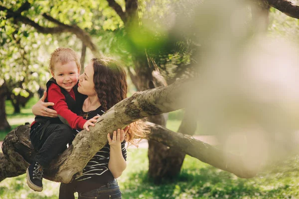 Mãe feliz e filho da criança brincando juntos ao ar livre e árvore de maçã escalada na primavera ou verão — Fotografia de Stock