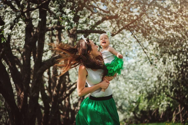 Glückliche Mutter und kleine Tochter genießen Spaziergang im frühlingshaft blühenden Garten oder Park — Stockfoto