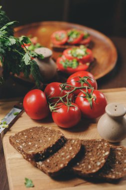 tost sandviç taze domates, yeşil soğan ve ahşap plaka üzerinde karanlık rustik iç kepekli ekmek yemek