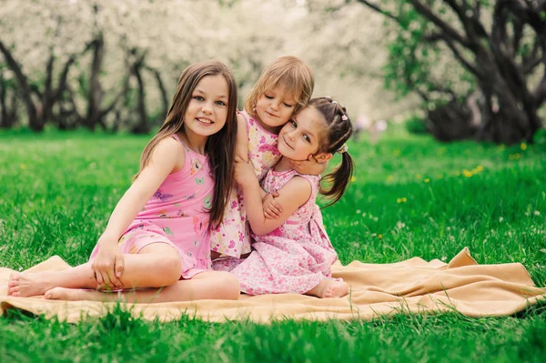 Three little sisters having a lot of fun playing together outdoor in summer park on vacation — Stock Photo, Image