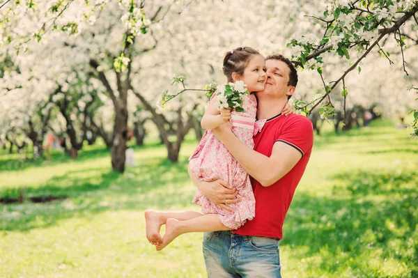 Pai feliz brincando com filha criança no passeio no jardim florescendo primavera — Fotografia de Stock