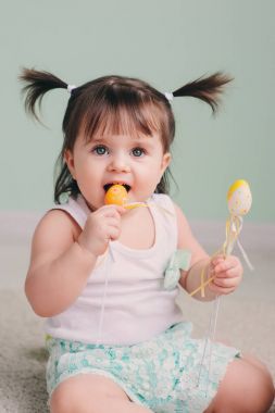 Dikey kapalı Paskalya süsleri ile oynarken şirin mutlu bebek kız portresi yakından