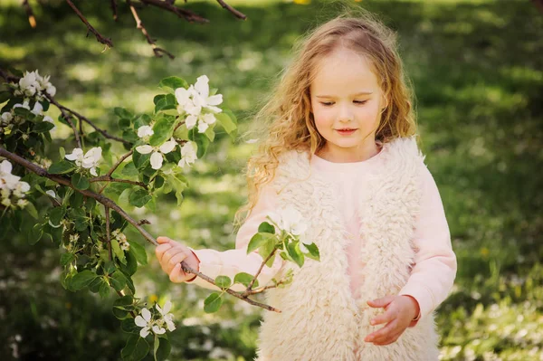 Våren porträtt av vackra drömmande lockigt 5 år gamla barn flicka vandrar i blommande trädgård — Stockfoto