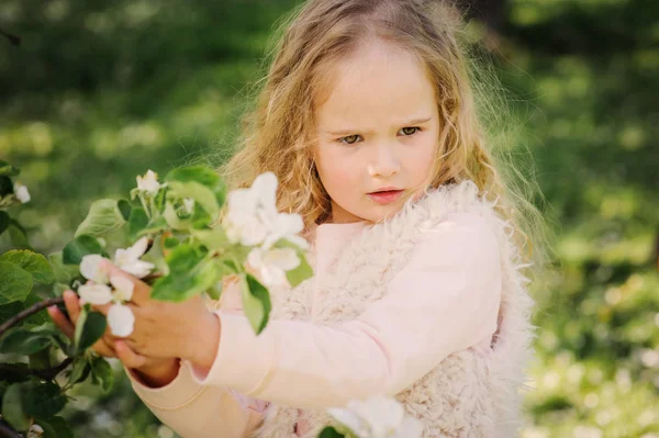 Lente portret van prachtige dromerig krullend 5 jaar oud kind meisje wandelen in bloeiende tuin — Stockfoto