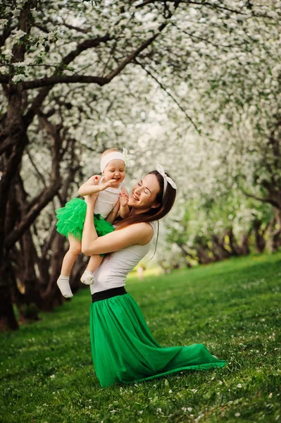 Retrato de primavera de mãe e bebê filha jogando ao ar livre em roupa combinando - saias longas e camisas. Família feliz enjoyng férias — Fotografia de Stock