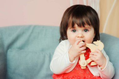 Şirin, mutlu bir kız bebek evde tahta oyuncaklarla oynuyor. Modern anaokulu, erken öğrenim konsepti