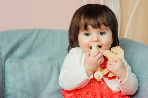 Симпатичная счастливая годовалая девочка, играющая дома с деревянными игрушками. Современный интерьер детского сада, концепция раннего обучения — стоковое фото