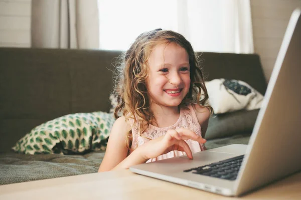 Enfant heureux en utilisant un ordinateur portable à la maison. École fille apprentissage avec ordinateur et internet intérieur . — Photo