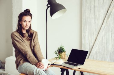 genç güzel blogger kadın evde laptop ve kahve ile sabah alışveriş online. Modern İskandinav iç ev ofis
