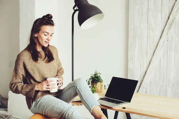 Young beautiful blogger woman shopping at home online with laptop and cup of coffee in the morning. Home office in modern scandinavian interior — Stock Photo, Image