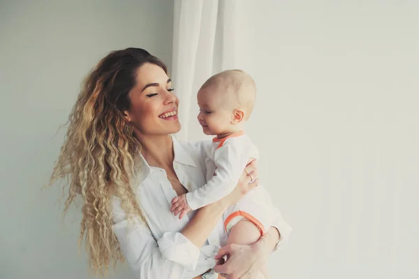 Famille heureuse à la maison. Mère tenant bébé fils dans la chambre dans le week-end matin confortable — Photo