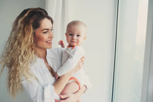 Famille heureuse à la maison. Mère tenant bébé fils dans la chambre dans le week-end matin confortable — Photo