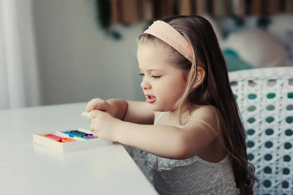 Linda niña jugando con plastilina o jugar masa en casa. Aprendizaje infantil para trabajar con arcilla de modelado — Foto de Stock