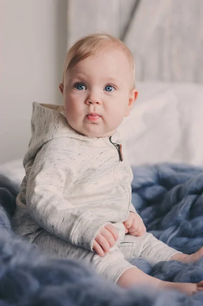 Portrait de bébé mignon de 8 mois assis sur le lit sur une couverture tricotée à la maison — Photo