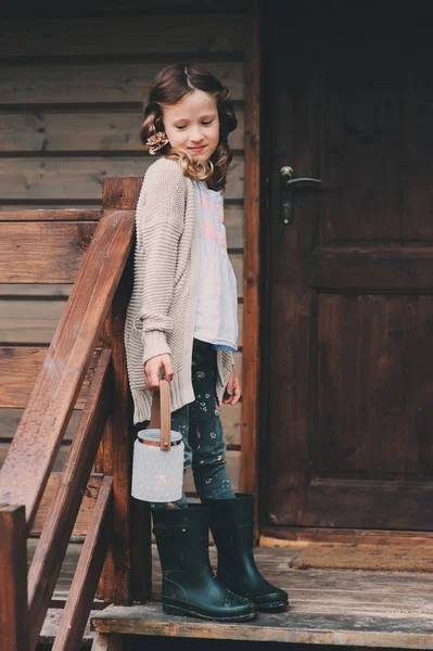 Child girl with candle holder relaxing in evening at cozy country house. Kid spending summer vacation in log cabin in the woods — Stock Photo, Image